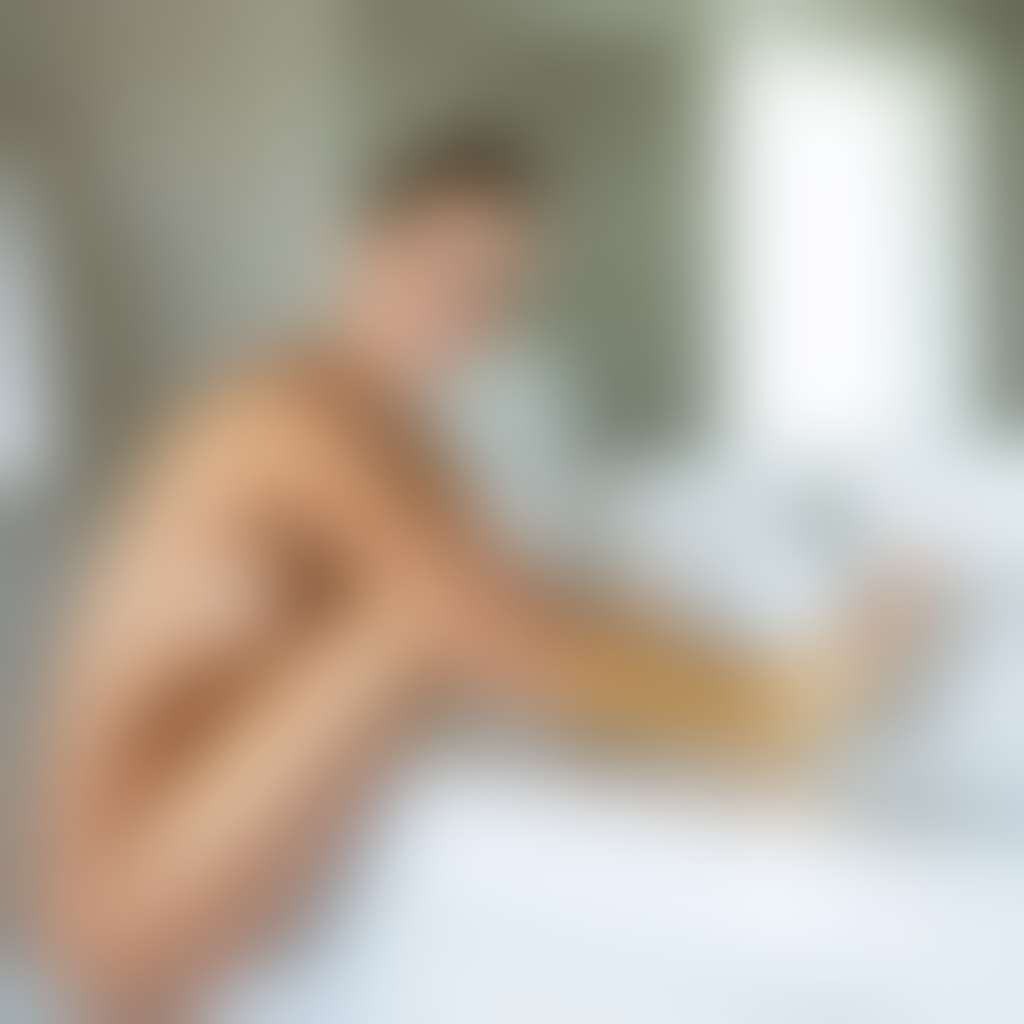 Femme appliquant de l autobronzant sur sa jambe avec un gant dans une salle de bain lumineuse pour obtenir un resultat uniforme sans traces